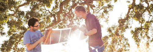 Two people holding a solar cell outdoors