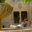 A girl studies at the fountain outside Green Library