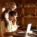 Man working at home with child on his shoulders.