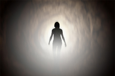 Silhouette of a person walking through a tunnel toward a bright light /Photo: Piotr Zabicki/ iStock.com