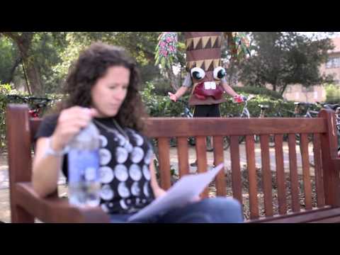 Video still image of a woman sitting on a bench reading. The Stanford Treeree is in the background.