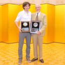 Photo – Ratner and Galayda holding with awards in front of yellow paneling