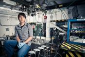 Photo - Ken Soong seated in front of a vacuum chamber for experiments.